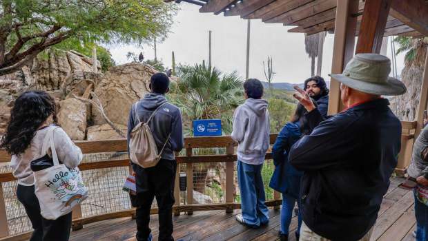 At the San Diego Zoo Safari Park's Condor Ridge space, volunteer Jacey Humes, at right with hat, speaks to a group of visiting science students from Moreno Valley. Two California condors can be seen in the distance. (Charlie Neuman / For The San Diego Union-Tribune)