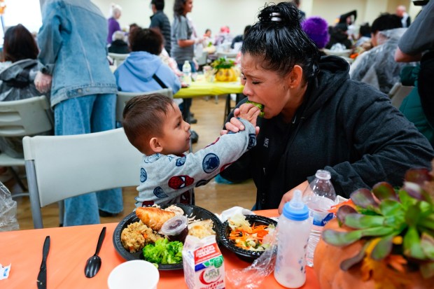At the annual Thanksgiving Dinner hosted by the San Diego Rescue Mission, Ali Puentes serves vegetables from his plate to his mother, Rossana Puentes, 40. The Puentes family is currently living out of their car. (Nelvin C. Cepeda / The San Diego Union-Tribune)