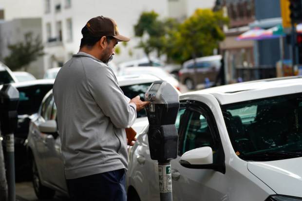 Carlos Perez used his credit card to pay a parking meter on Fifth Avenue between University and Robinson Avenues on Thursday, Nov. 20, 2025. (Nelvin C. Cepeda / The San Diego Union-Tribune)