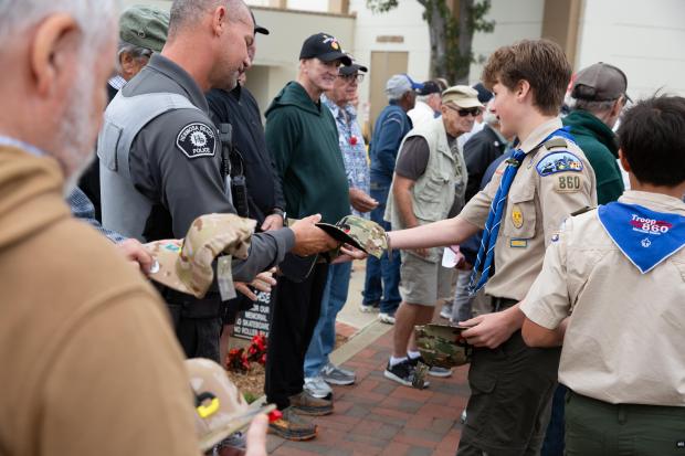 Boy scouts hand out free camouflage hats to veterans during...