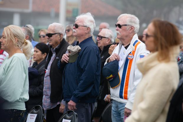 Veterans, family members and local residents stand up during a...
