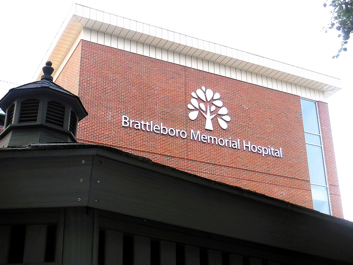 The exterior of Brattleboro Memorial Hospital with its name and tree logo displayed on a red brick wall.