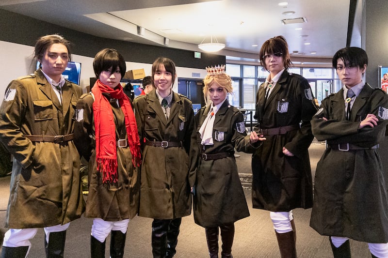A group of six friends cosplay as characters in "Attack on Titan" at the concert, wearing signature uniforms from the anime.