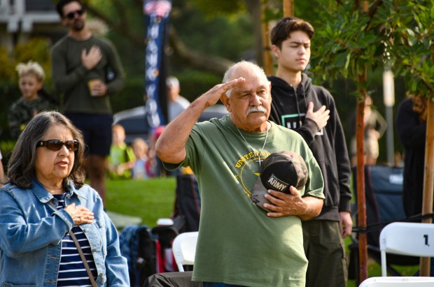 Army Veteran Felipe Guzman salutes during the National Anthem as...