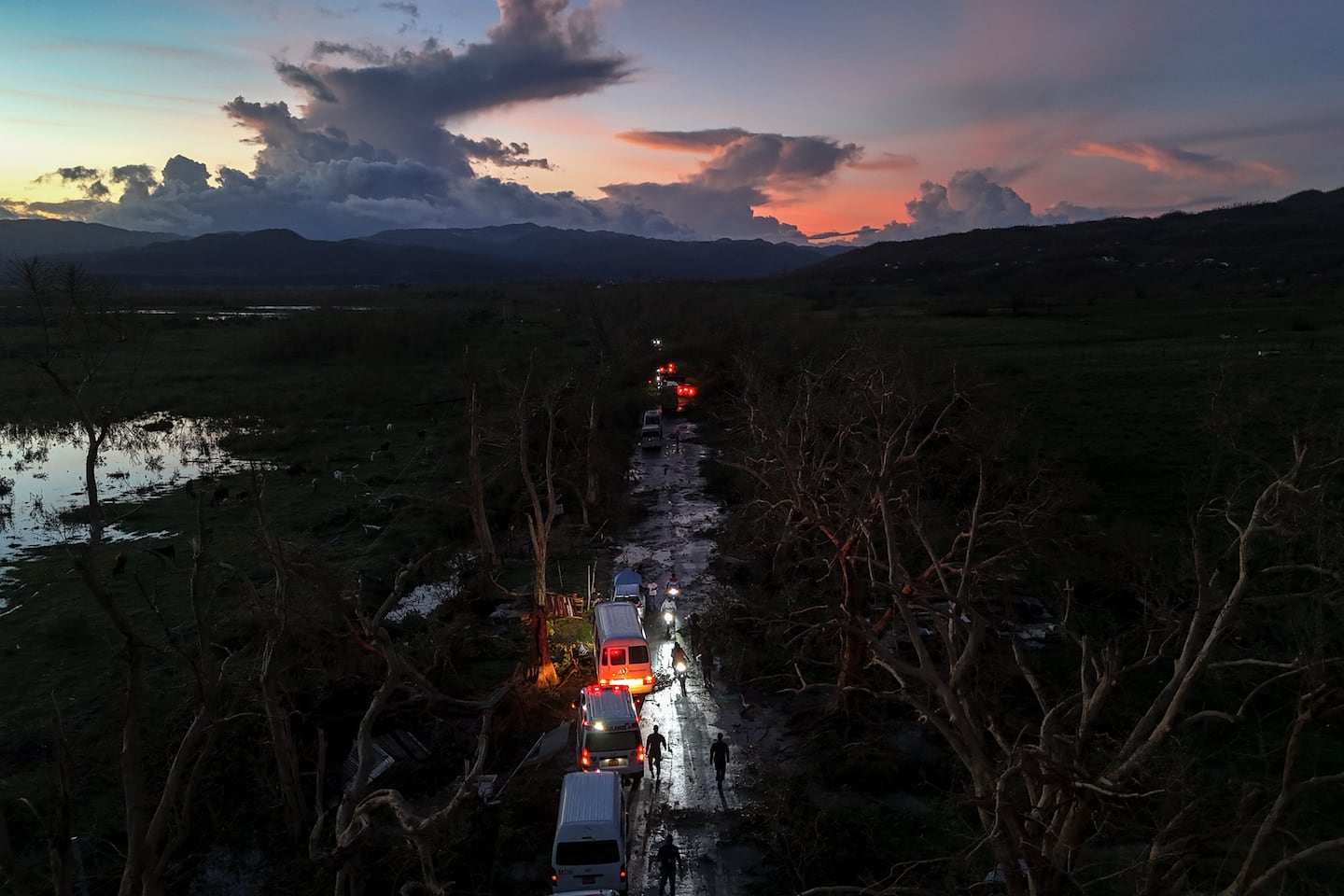 A convoy carrying aid to Black River, which was hit by Hurricane Melissa, makes its way through Holland Bamboo, Jamaica, on Wednesday, where downed trees and debris partially blocked roads.