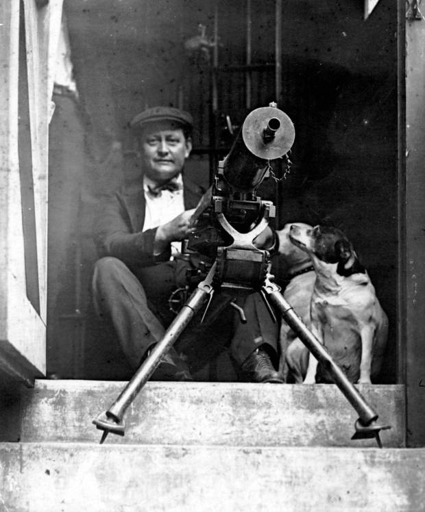 A man armed with a machine gun sits at the...