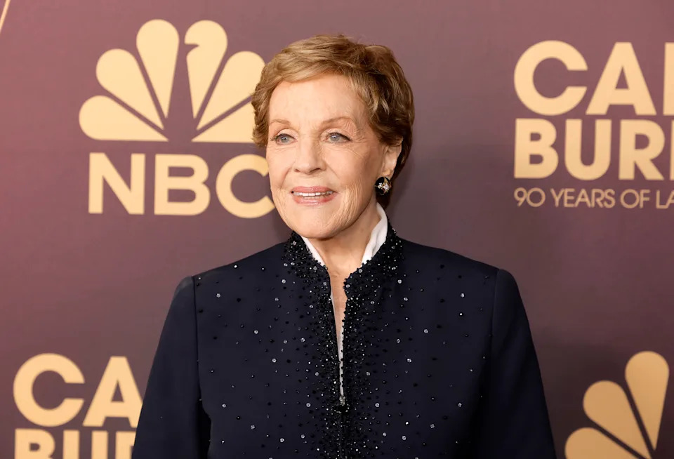 Julie Andrews in elegant, beaded jacket at an event backdrop with NBC and 90 Years of Laughter logos
