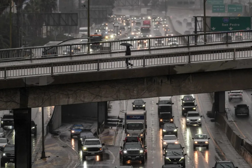 A pedestrian with an umbrella walks on a bridge over the rain-soaked 110 Freeway in Los Angeles Friday, Nov. 14, 2025. (AP Photo/Jae C. Hong)