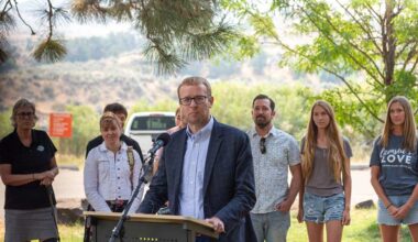 Idaho Department of Health and Welfare Director Alex Adams joins state officials and business leaders to announce the Idaho State Park Foster Family Passport at Lucky Peak State Park, as foster parents and families stand behind him. (Kyle Pfannenstiel/Idaho Capital Sun)