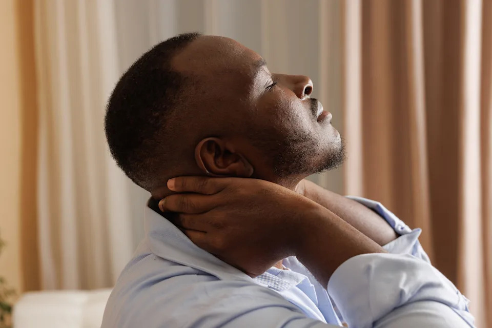Man touching his neck, experiencing pain and discomfort, symbolising stress and muscle tension