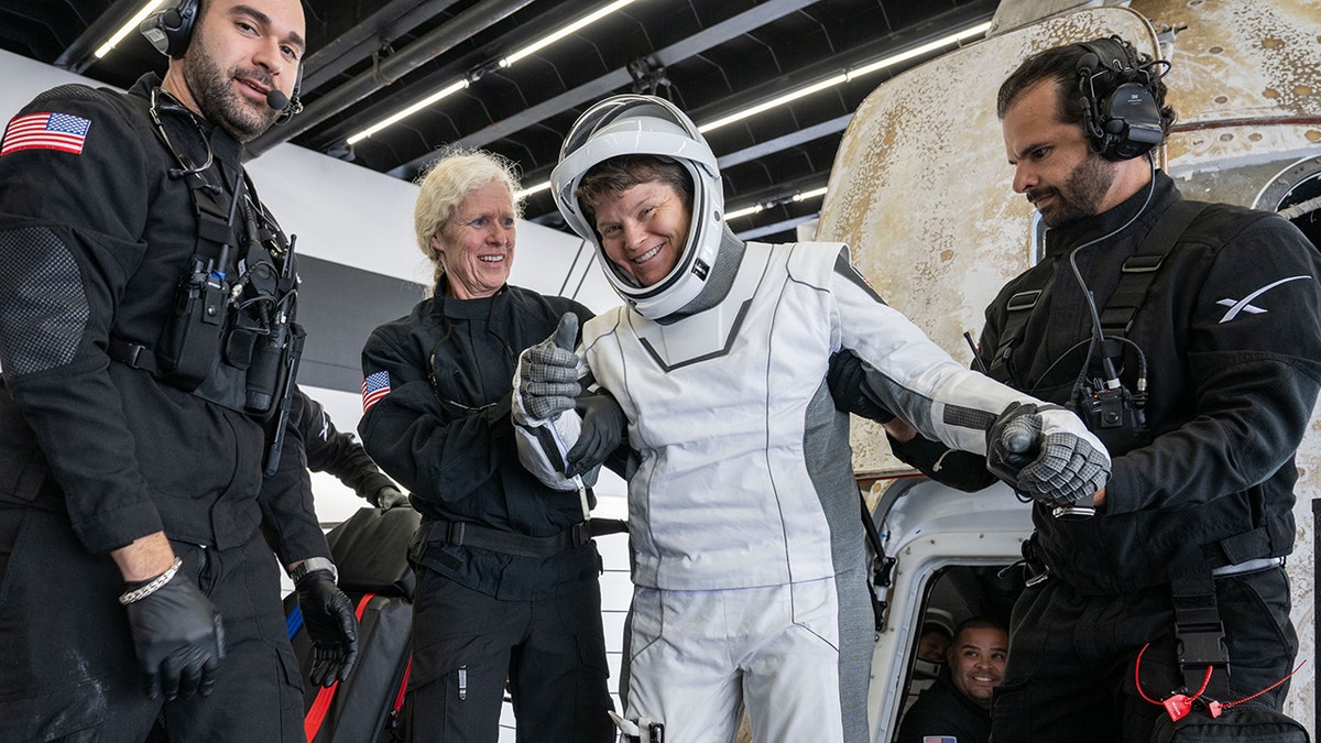 NASA astronaut Anne McClain helped out of spacecraft