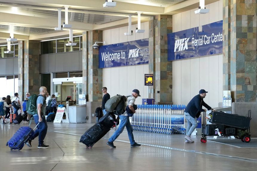 Passengers head to the rental car center at Phoenix Sky Harbor International Airport in Phoenix on Saturday.