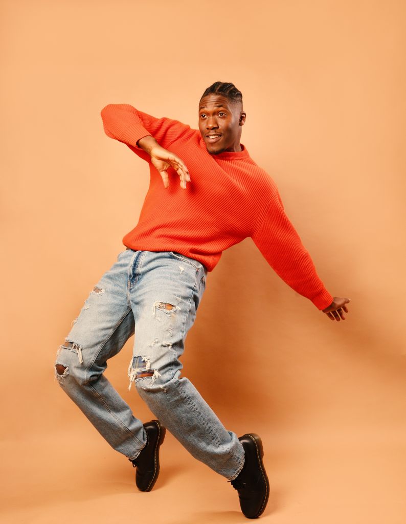 Man in jumper and jeans dancing energetically 