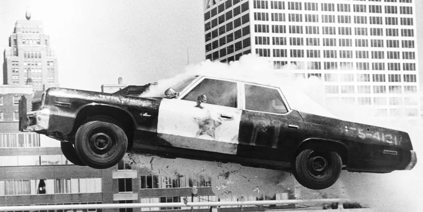 A police car jumps over an obstacle while smoke rolls out over the engine