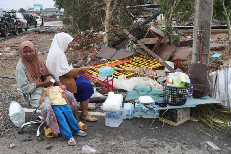 A family feeds a young child after floodwater receded in devastated Hat Yai district of Songkhla on Nov 28. (Photo: Nutthawat Wichieanbut)