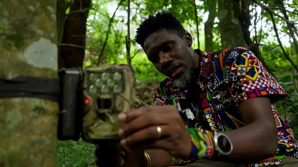 Wildlife biologist Mwezi Mugerwa fits a camera trap to a tree. - Courtesy of Indianapolis Prize