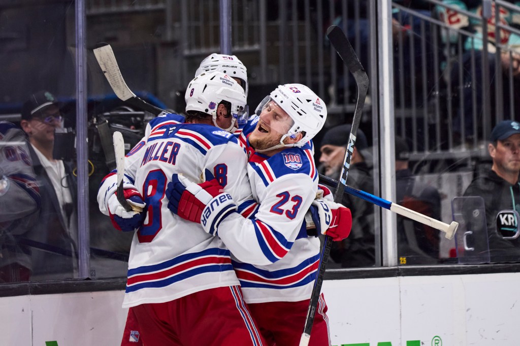New York Rangers players Adam Fox (23) and J.T. Miller (8) celebrate a win against the Seattle Kraken.