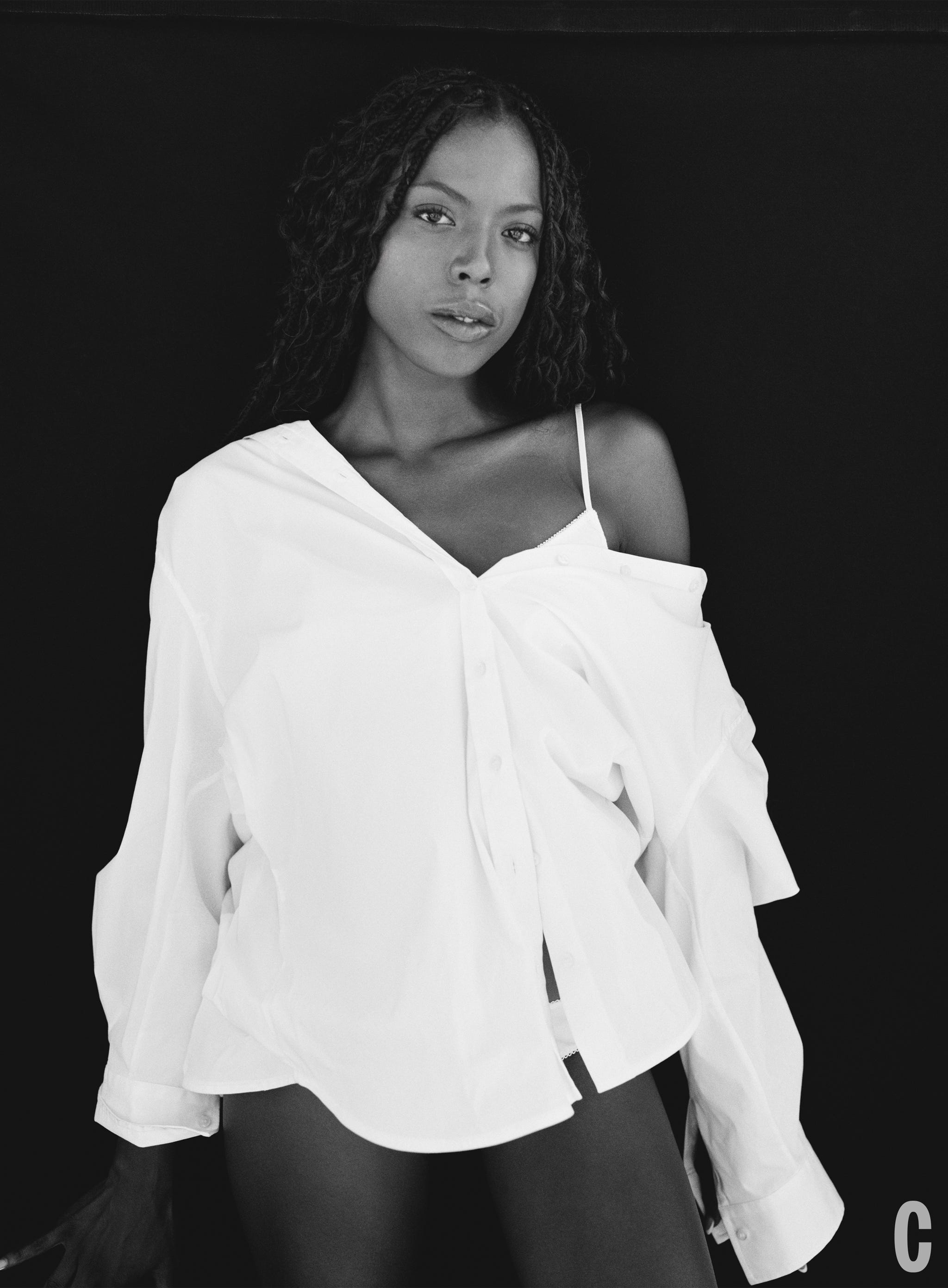 a model wearing a partially unbuttoned white shirt against a dark background