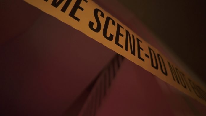 crime-scene-yellow-tape-put-up-by-a-officer-after-a-murder-of-a-woman-SBI-350878512