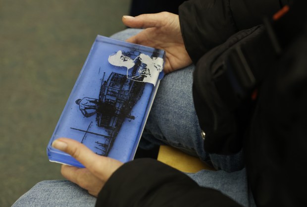 An attendee holds a sample glass brick used in the Chicago Race Riot of 1919 Commemoration Project during a panel discussion at the Harold Washington Library, Nov. 8, 2025, in Chicago. (John J. Kim/Chicago Tribune)