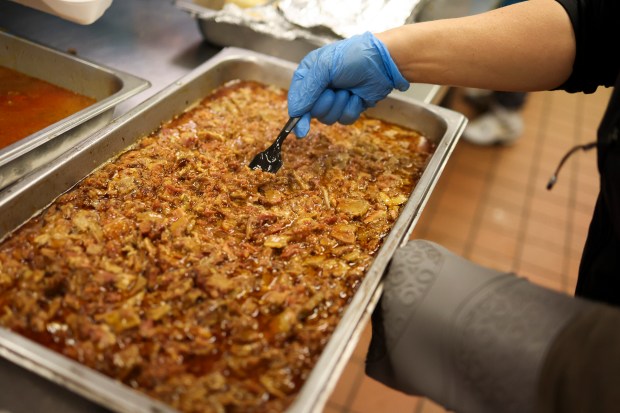 Fight2Feed founder Jiwon McCartney stirs a tray of pulled pork...