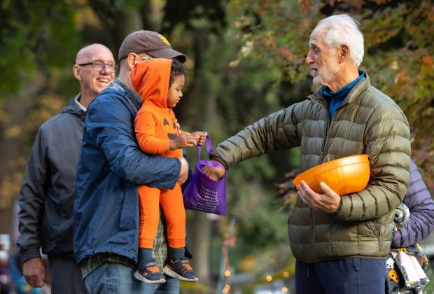 Ben Meyer-Abbott, of Evanston, and his nephew, Nikolai Meyer-Abbott, 1, trick-or-treat on Monroe Street in Evanston on Oct. 31, 2025. (Dominic Di Palermo/Chicago Tribune)