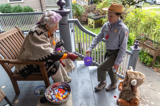 Jerri Zbiral, left, hands out candy to Malia Bowers, center, dressed as a park ranger, and her son Sullivan Bowers, 4, dressed as a bison, during trick-or-treating on Monroe Street in Evanston on Oct. 31, 2025. (Dominic Di Palermo/Chicago Tribune)