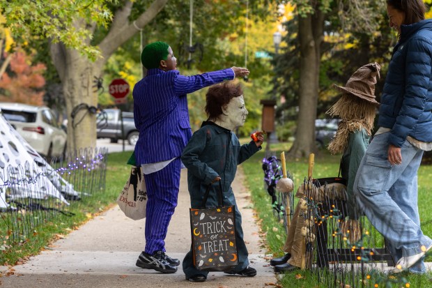 Zyaire Harris, 10, dressed as the Joker, and Kace Martin, 5, dressed as Michael Myers, react as an animatronic scarecrow scared them during trick-or-treating on Monroe Street in Evanston on Oct. 31, 2025. (Dominic Di Palermo/Chicago Tribune)