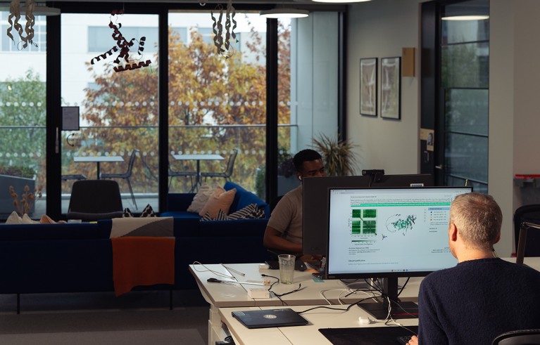 People working at computers. One screen shows a proposed protein structure.