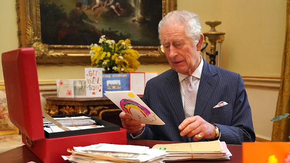 King Charles looking at a get-well soon card from his office.