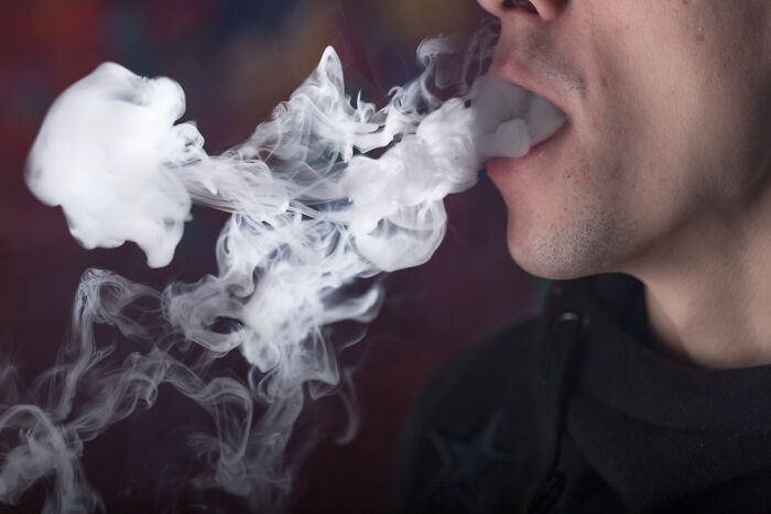 Person exhaling thick white smoke, illustrating the concept of Dr. Google versus real doctor health debates.