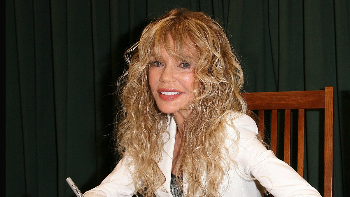 Dyan Cannon smiling while signing her memoir at a book signing.