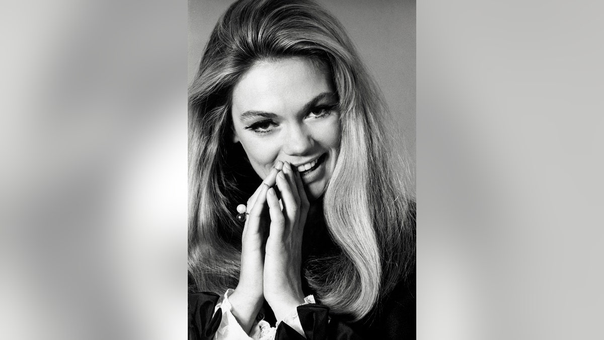 Dyan Cannon smiling in a prayer pose.