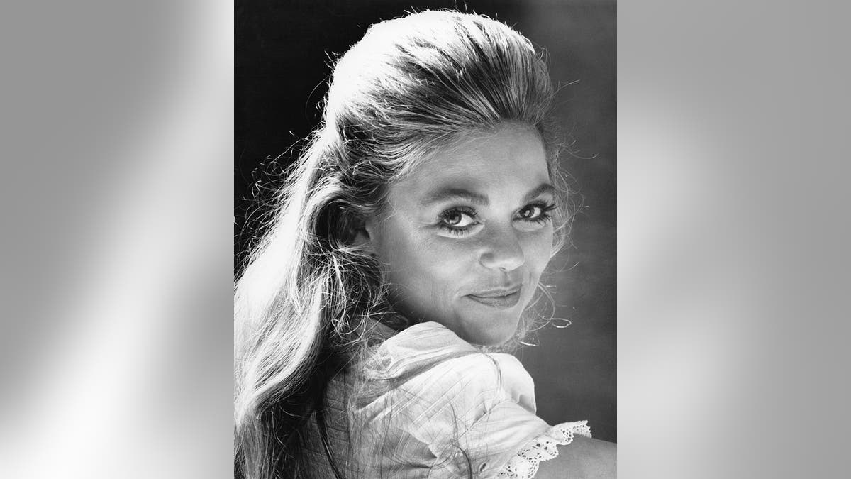 A young Dyan Cannon with her head turned and smirking at the camera.