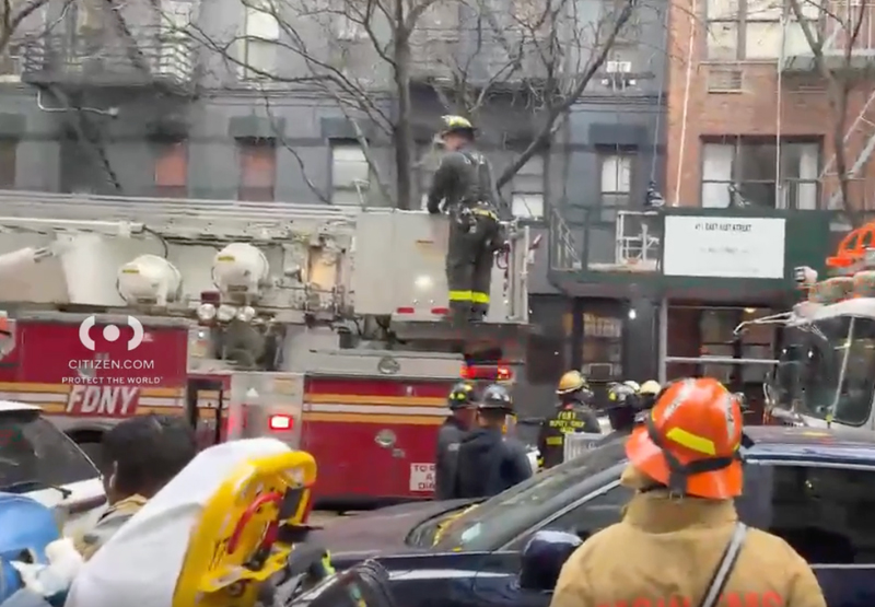 Firefighters and emergency vehicles responding to an apartment fire in a city.