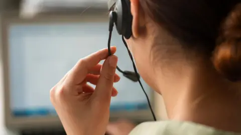 Getty Images A woman wearing a phone headset at a call centre