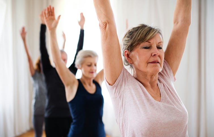 Older people at an exercise class with their arms in the air