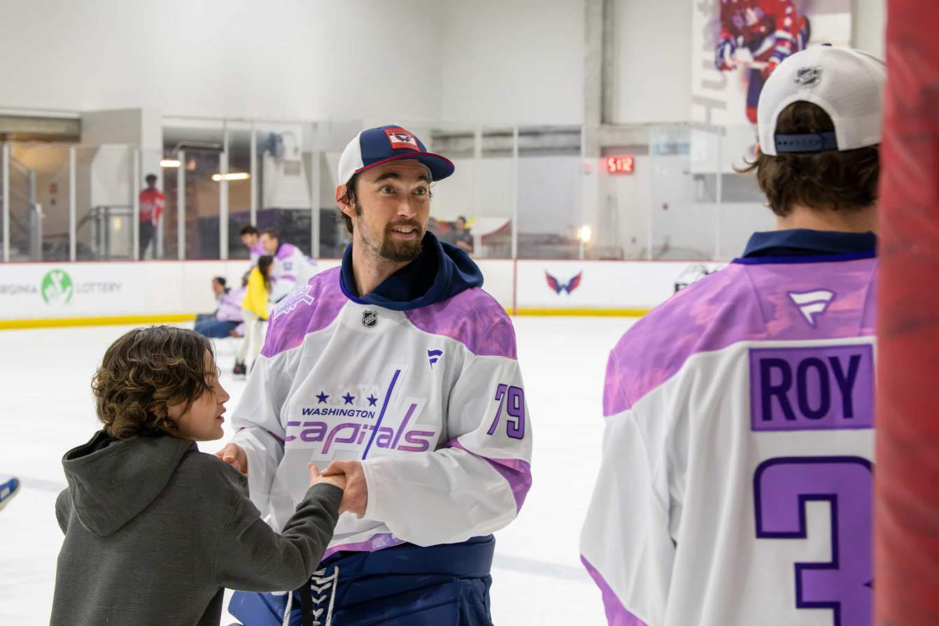 Charlie Lindgren and a child on the ice during the Hockey Fights Cancer skate.
