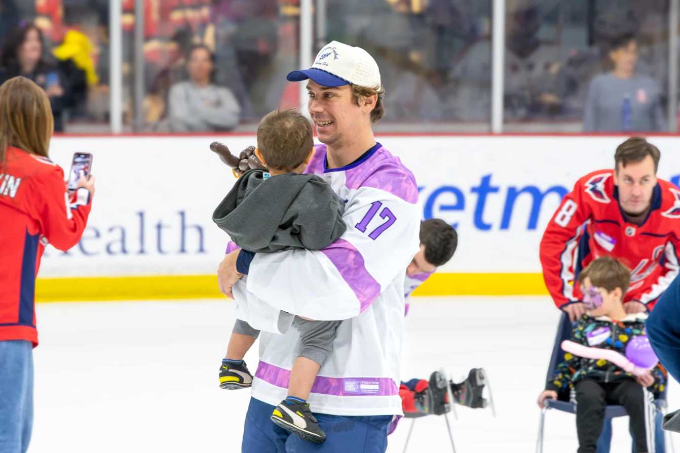 Dylan Strome holds a child on the ice during the Hockey Fights Cancer skate