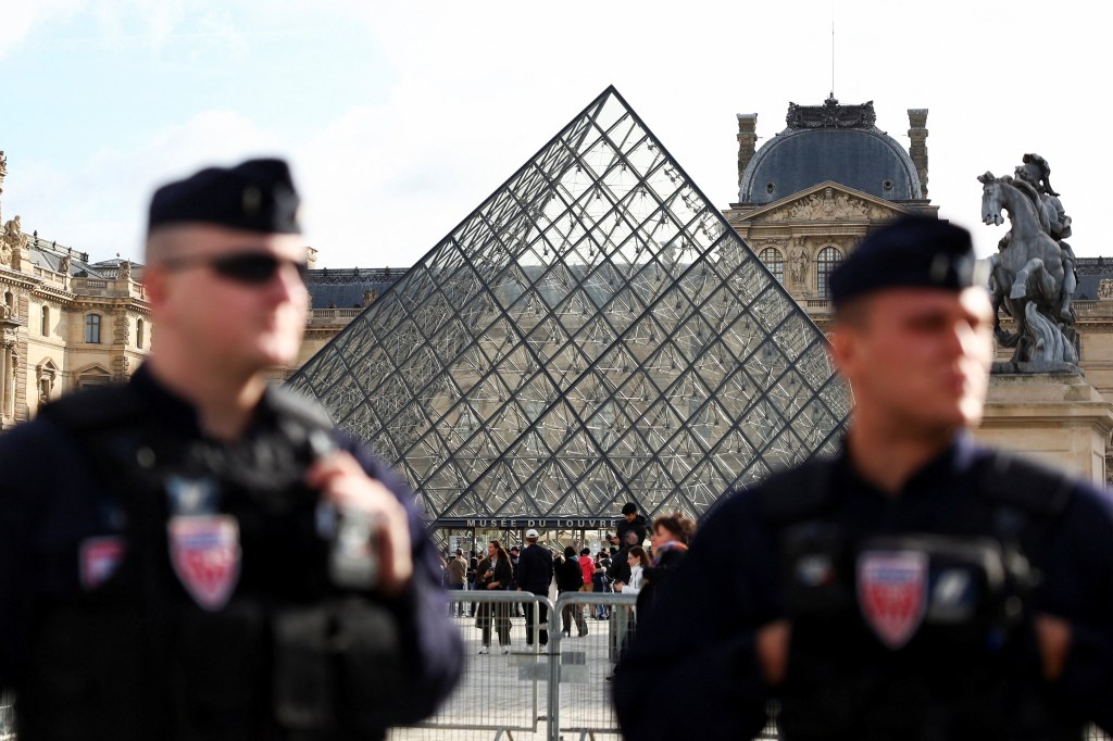 French riot police officers stand near the Louvre Museum's glass pyramid after suspects were arrested in a heist case.