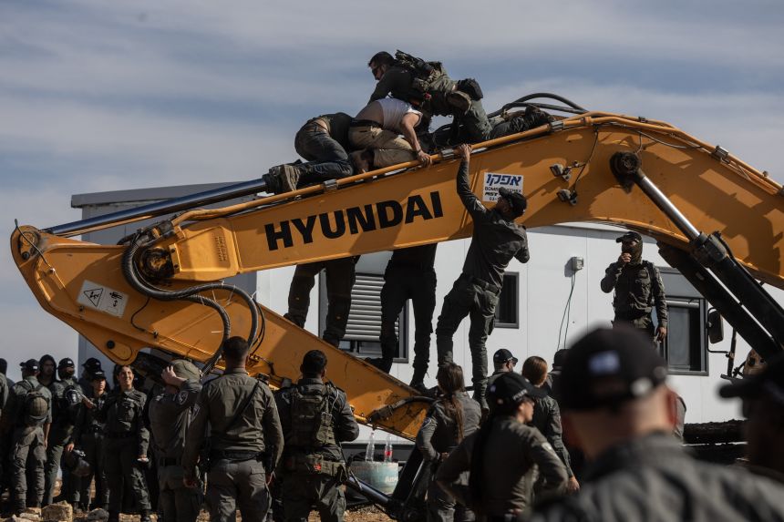 Israeli security forces clash with Hilltop Youth on an earth mover as they evacuate and demolish an illegal outpost built near the Jewish settlement of Metzad.