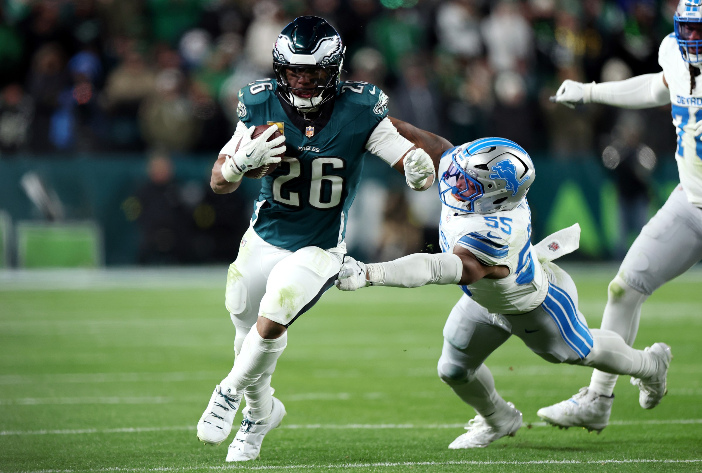 PHILADELPHIA, PENNSYLVANIA - NOVEMBER 16: Saquon Barkley #26 of the Philadelphia Eagles is pursued by Derrick Barnes #55 of the Detroit Lions during the second half of a game at Lincoln Financial Field on November 16, 2025 in Philadelphia, Pennsylvania. (Photo by Emilee Chinn/Getty Images)