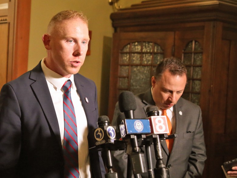 Man speaks into news microphones