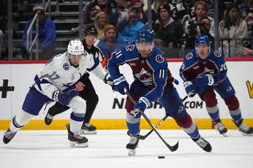 Colorado Avalanche center Brock Nelson (11) heads down the ice with the puck as center Ross Colton, back right, and Tampa Bay Lightning center Dominic James pursue in an NHL hockey game.