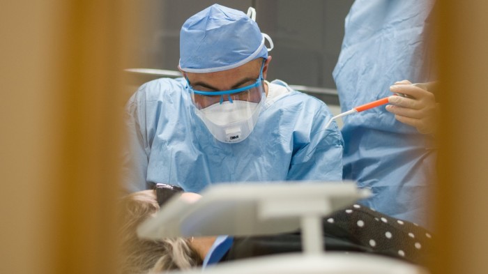 A dentist works on a patient at a practice in London
