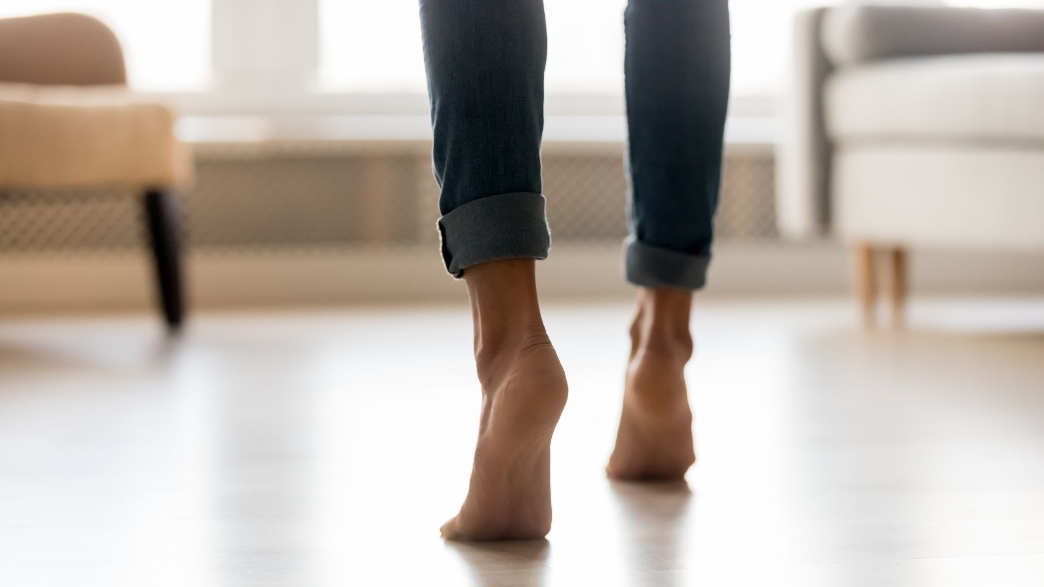 Barefoot person walks on tiptoes, seen from calf down