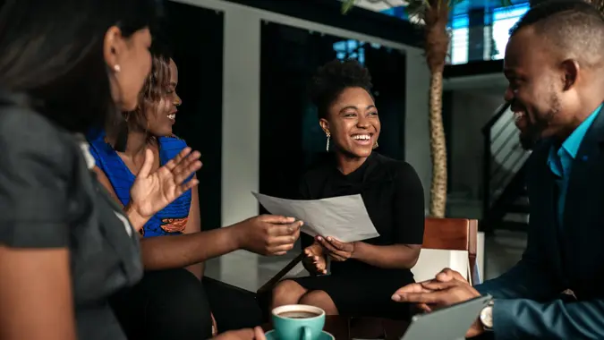 A group of young professionals meeting up and chatting, smiling.