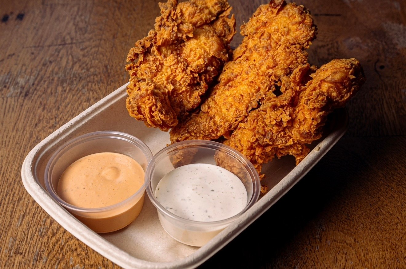 Three chicken tenders in a paper boat with sauces.
