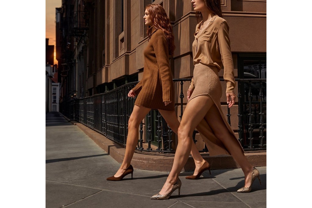 Two women in brown and tan dresses walk along a city sidewalk.