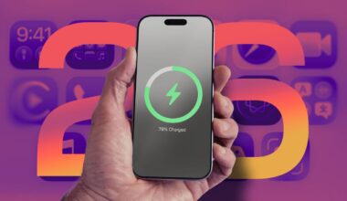 A hand holds an iPhone with a battery charging status in front of the number "26" and application icons in the background.